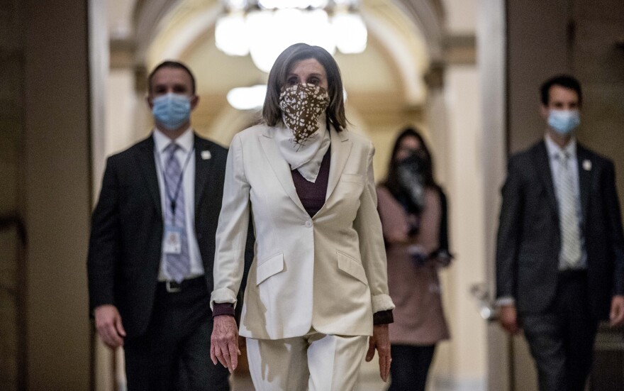 House Speaker Nancy Pelosi, wearing a face covering, walks to her office on Capitol Hill Thursday after signing the latest coronavirus relief package.