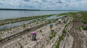 FILE - People walk through a part of the Amazon River that shows signs of drought in Santa Sofia, on the outskirts of Leticia, Colombia, Oct. 20, 2024. (AP Photo/Ivan Valencia, File)