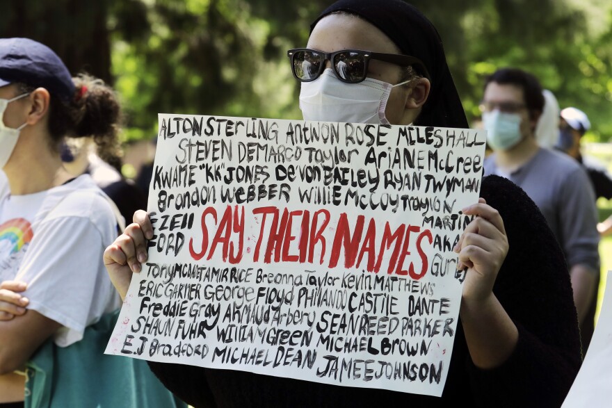 A person holds a sign Monday, June 1, 2020, with the names of George Floyd and others who have died, in Tacoma, Wash., during a protest against police brutality and the death of Floyd, a black man who died after being restrained by Minneapolis police offi