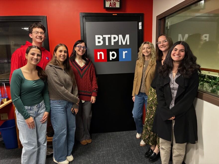 YAAC from left to right: Emma Gillies, Reed GianGrasso, Hailey Muscarella, Gracie Wenner, Madeline Dorobiala, Caroline Stenard, Violet Ceppaglia standing in front of the BTPM NPR door.