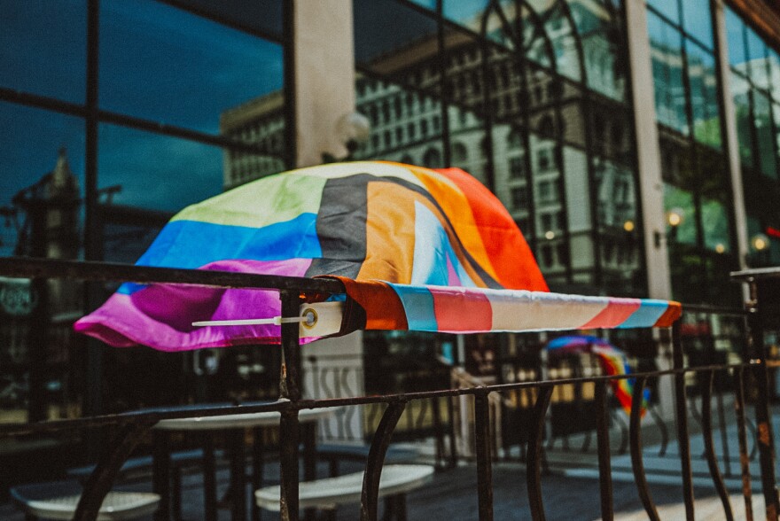 A pride flag blowing in the wind on a railing.