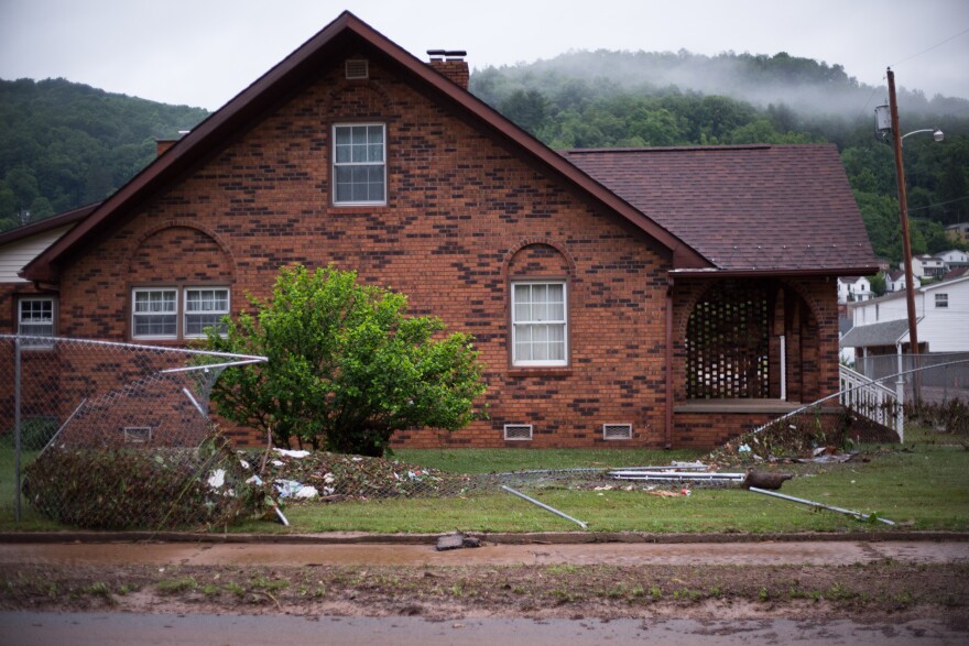 A mangled metal fence tangles with floodwater debris beside a downtown Richwood home.