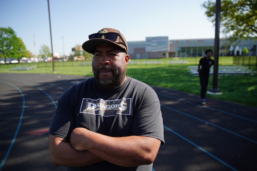 East Tech boys track and field head coach Michael Hardaway stands arms crossed on a track.