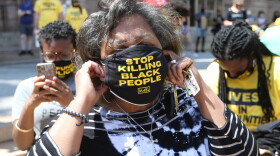 St. Louis Comptroller Darlene Green puts on a mask during a Juneteenth celebration at St. Louis City Hall, where people called on the city to close the Workhouse and help Black transgender people.