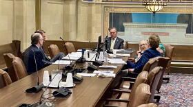 Oklahoma Treasurer Todd Russ, seen through a glass window, discusses options with attorneys during an executive session of the Tobacco Settlement Endowment Trust Board of Investors at the Capitol in Oklahoma City on Wednesday, July 1, 2026.