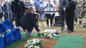 A man and child lay flowers on the headstone for the 2,411 fetal remains that were found in Dr. Ulrich Klopfer's garage in September 2019. The burial service was at Southlawn Cemetery in South Bend on Wednesday, Feb. 12, 2020.