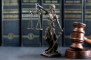 A justice statue rests on a desk next to a judge's gavel.
