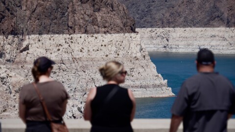 Tourists on the Hoover Dam look out at the bathtub ring of minerals that shows the former water levels of Lake Mead near Boulder City, Nev., on Friday, Aug. 7, 2026.