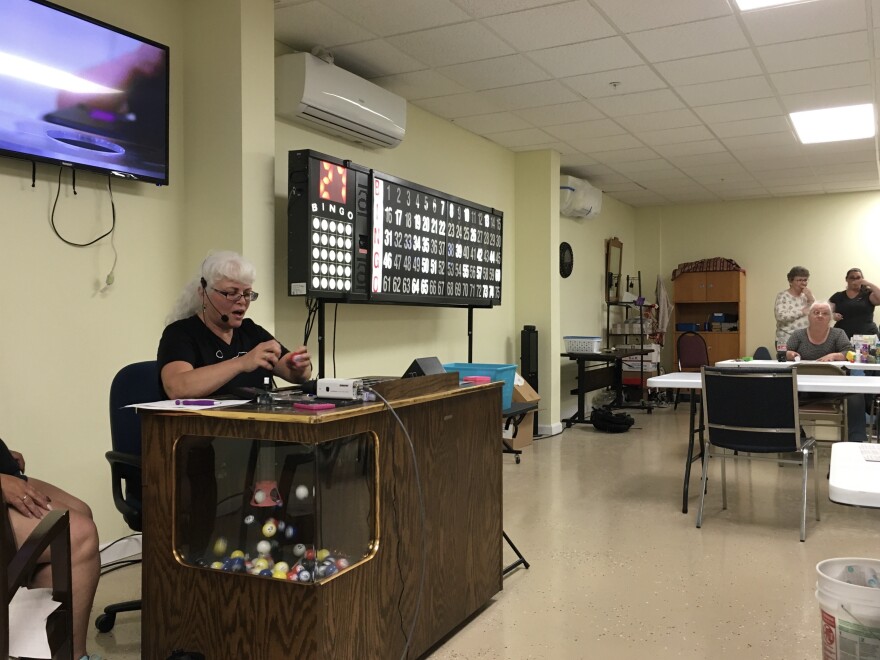 A woman sits at a table with bingo balls.