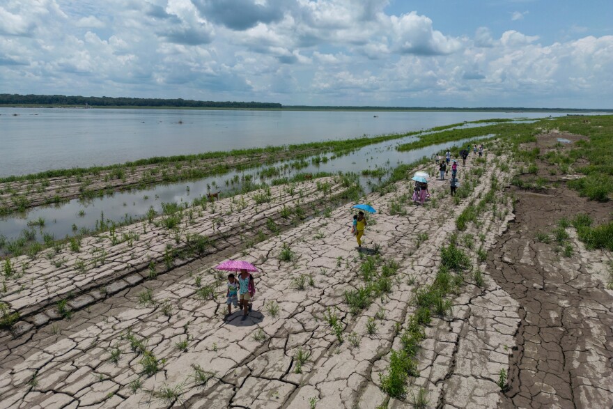 People walk through a part of the Amazon River that shows signs of drought