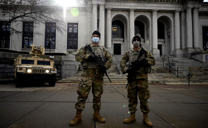 Connecticut Army National Guard Sgt. Steven Stosonig and Spc. Eric Lyhne stand watch in front of the state Supreme Court as a small group of demonstrators gather on the grounds of the state Capitol in Hartford on Jan. 20, 2021. There was a heavy security presence at capitols throughout the country on the day of President Joe Biden's inauguration due to threats of armed protests.