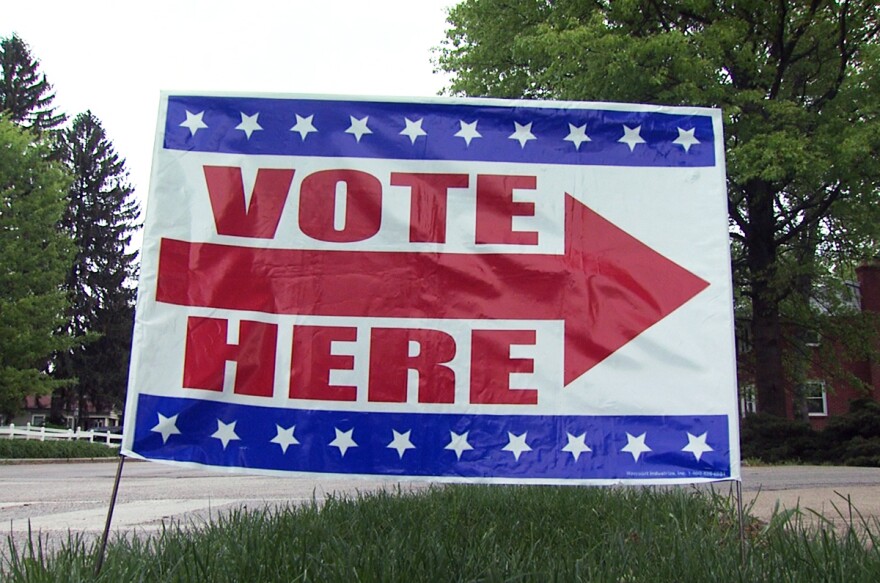  A red white and blue "vote here" sign points voters in the right direction to a polling place with a red arrow 