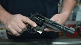 Hands holding a .357 Magnum revolver in a gun shop setting.
