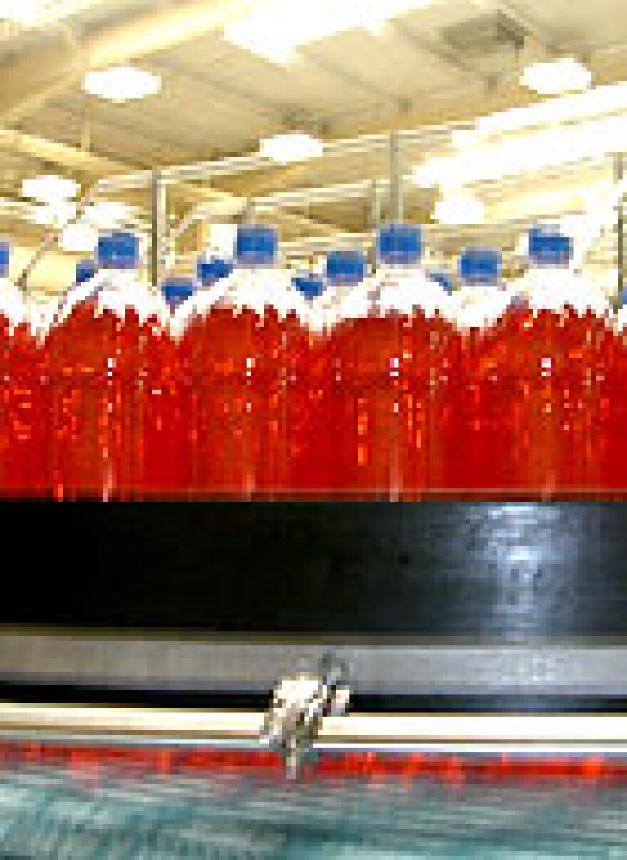 Bottles of IRN BRU roll by on a factory conveyor. In Scotland, the soda outsells Coca-Cola.