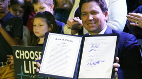 Florida Gov. Ron DeSantis holds up a 15-week abortion ban law after signing it on April 14, 2022, in Kissimmee. Florida later imposed a six-week ban. (AP Photo/John Raoux, File)