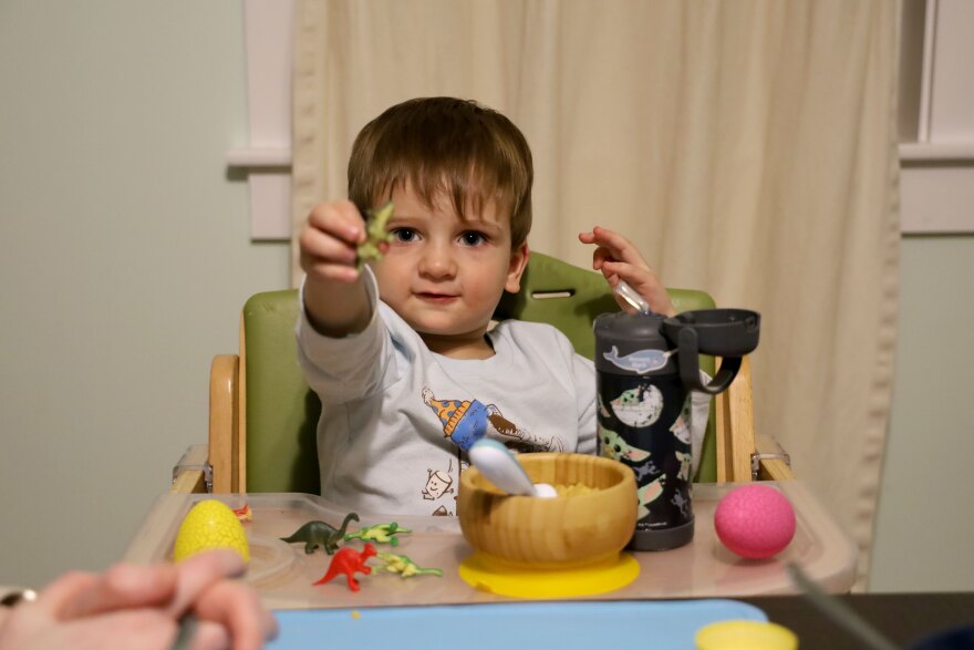 Bennett Black holds up a toy dinosaur at the Black dinner table in their home in Saco.