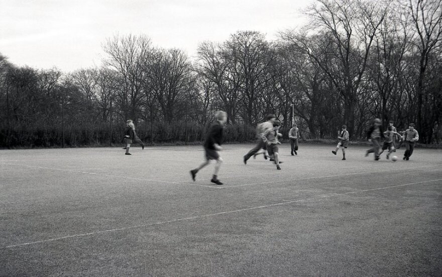 A group of schoolboys playing football outside on a large school playground, England, UK.