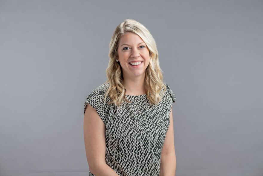 A woman smiles in front of a gray backdrop.