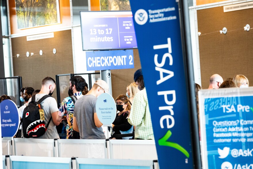 A TSA PreCheck sign near passengers standing in the line for TSA security