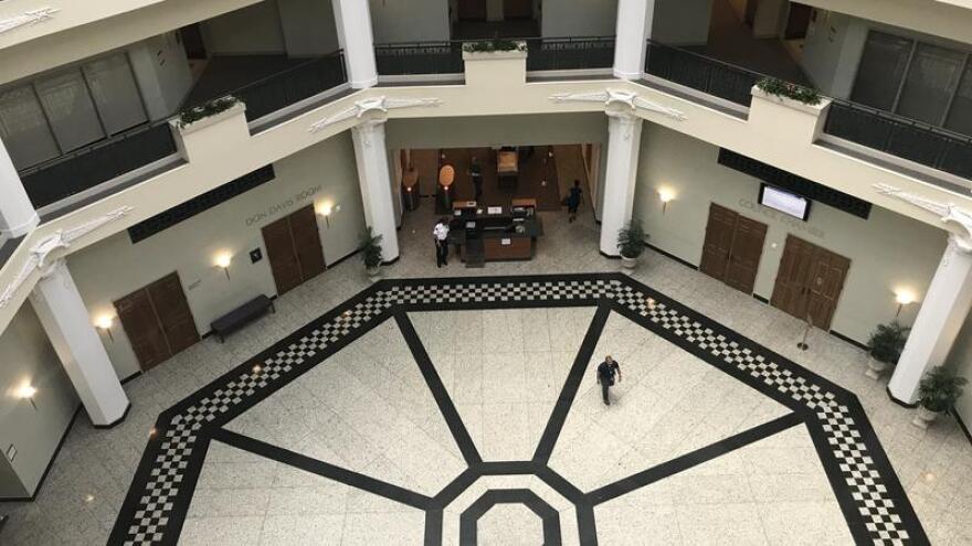 a large, open main lobby at the Jacksonville City Hall with a top down view, a few people walking along the bottom floor. 