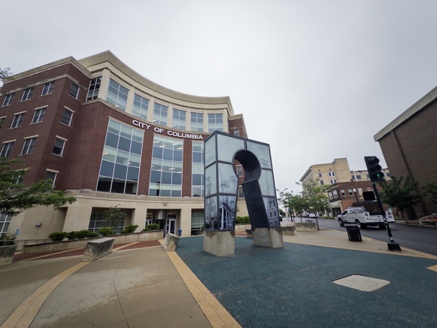 The exterior of Columbia's Daniel Boone City Building is shot looking upward from the streetlight facing Broadway. It is an overcast day. Eighth Street can be seen on the right vertical third of the photo with minimal traffic.