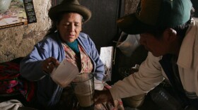A woman serves a glass of 'Chicha' to a client in the village of Pisaq near Cuzco, Peru. Chicha is a local alcoholic beverage made from sprouted or germinated corn.