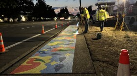 Two crew members of the Springfield Stormwater Team meld the mural onto the sidewalk