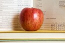 Stack of books and apple with a vintage report card