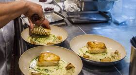 A worker arranges food onto plates in the kitchen of a restaurant in New York. (Brittainy Newman/AP)
