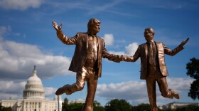 People take photos of a protest art representing President Donald Trump and Jeffrey Epstein 
