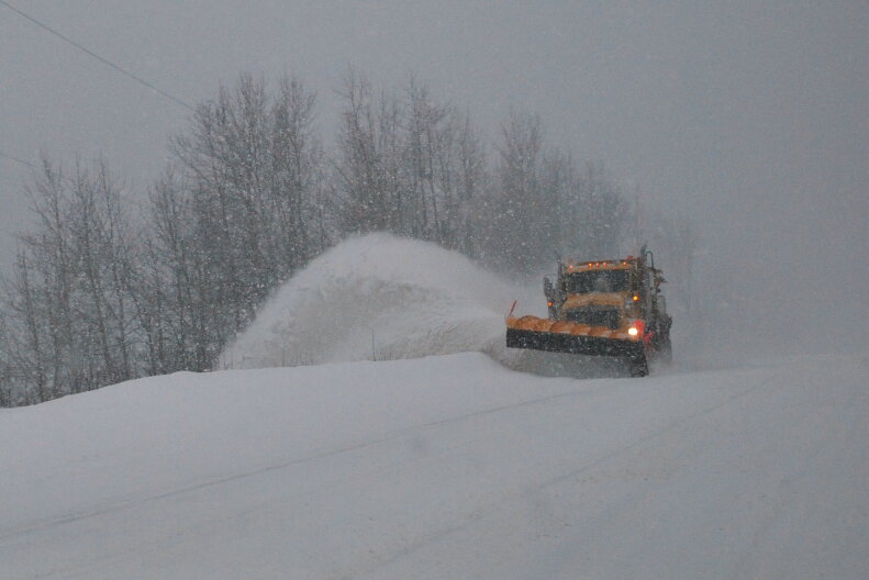 A snowplow works to clear a road.