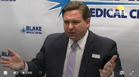 Governor DeSantis sits at a table and gestures with hands