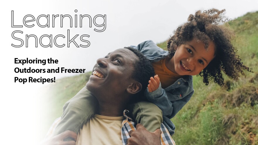 Girl sitting on father's shoulder while walking through nature