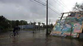 A cyclist rides past the iconic Everglades Wonder Gardens sign that damaged by Hurricane Irma in downtown Bonita Springs, Fla., Monday, Sept. 11, 2017. (Nicole Raucheisen/Naples Daily News via AP)