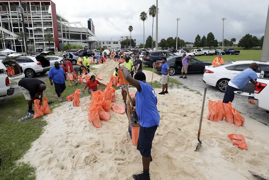 Orlando city employees and volunteers fill sandbags for residents as they prepare for Hurricane Irma, Friday, Sept. 8, 2017, in Orlando, Fla. Lines of vehicles stretched for miles and many waited several hours to get the sandbags. (AP Photo/John Raoux)
