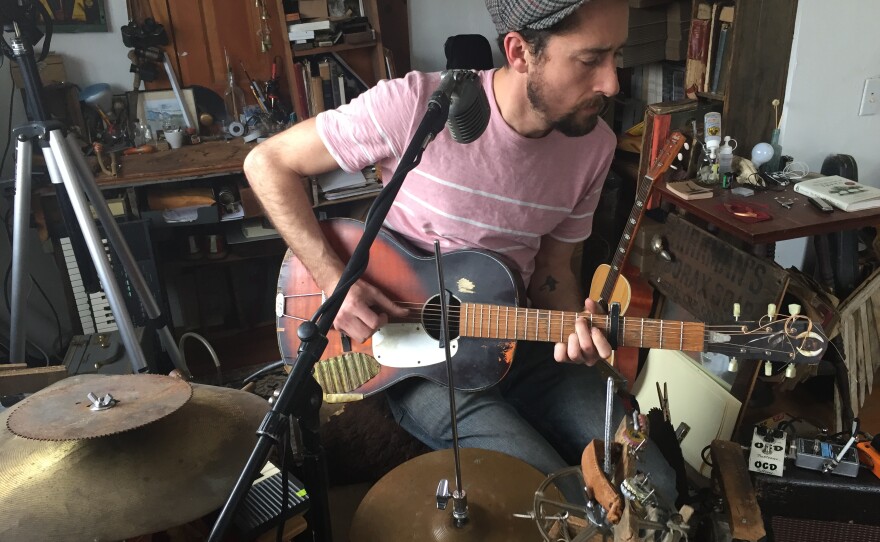 Matt Lorenz sits at a large contraption of homemade and traditional instruments.  