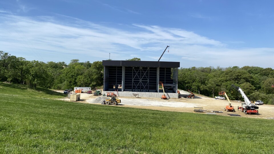 Construction equipment surrounds a large music festival stage being built.