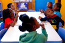 Legend, 4, left, and Paison, 3, right, look up at an education video while eating a snack on Monday, April 10, 2023, at the childcare center in Penrose.
