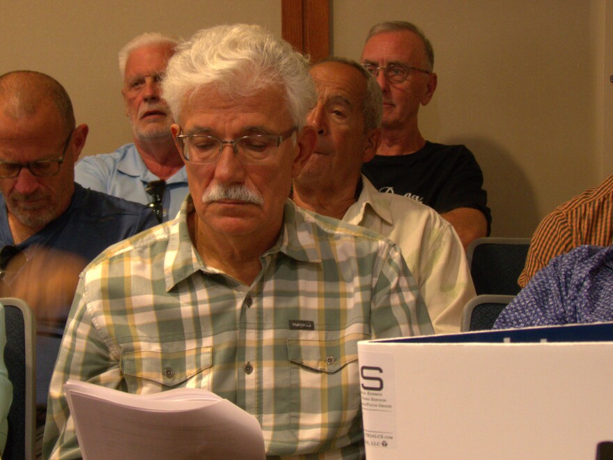 Man with tray hair and mustache looking down at papers