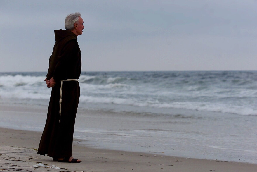 In this July 17, 2000, file photo, the Rev. Mychal Judge, the Fire Department of New York's chaplain with the New York City Fire Department, stands at the shore before a service to remember the 230 people who died on July 17, 1996, in the explosion of TWA Flight 800, at Smith Point Park in Shirley, N.Y. Judge joined relatives for the Flight 800 memorial service every year until 2001, when six weeks later Judge himself was killed in the Sept. 11 terror attacks at the World Trade Center.