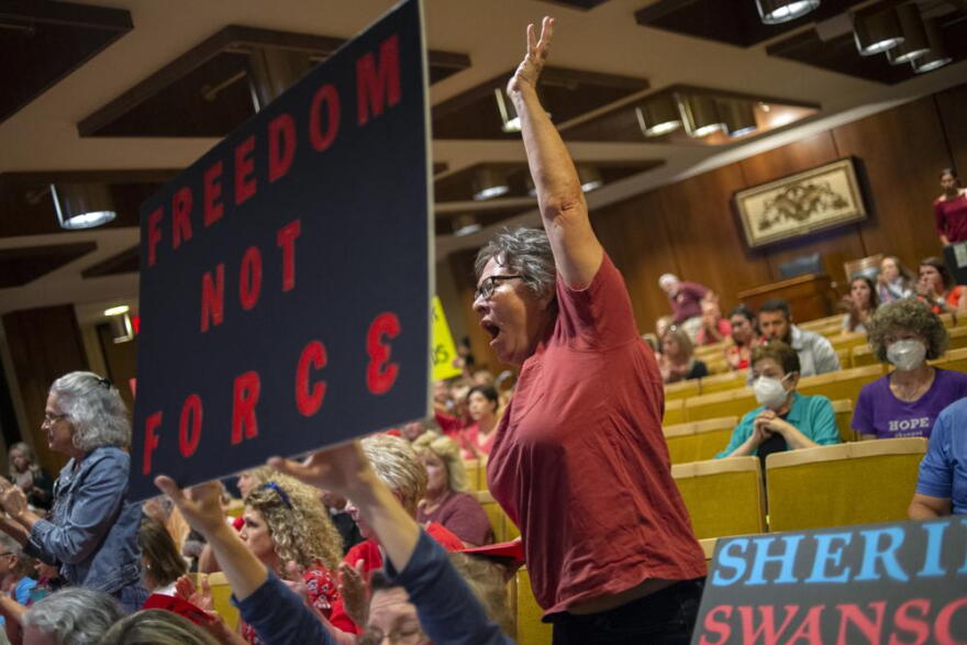 A Fenton resident cheers on a speaker who opposes the mask mandate as more than 100 people pack the Harris Auditorium as parents and county residents share opinions about the county's K-6 school mask mandate during public comment at a Genesee County Board of Commissioners meeting on Monday, Aug. 30, 2021, at the county administration building in downtown Flint, Mich.