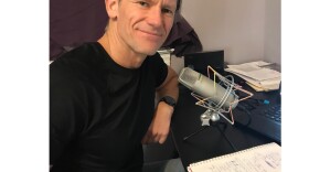 Dr. Chris White sits in front of a microphone.