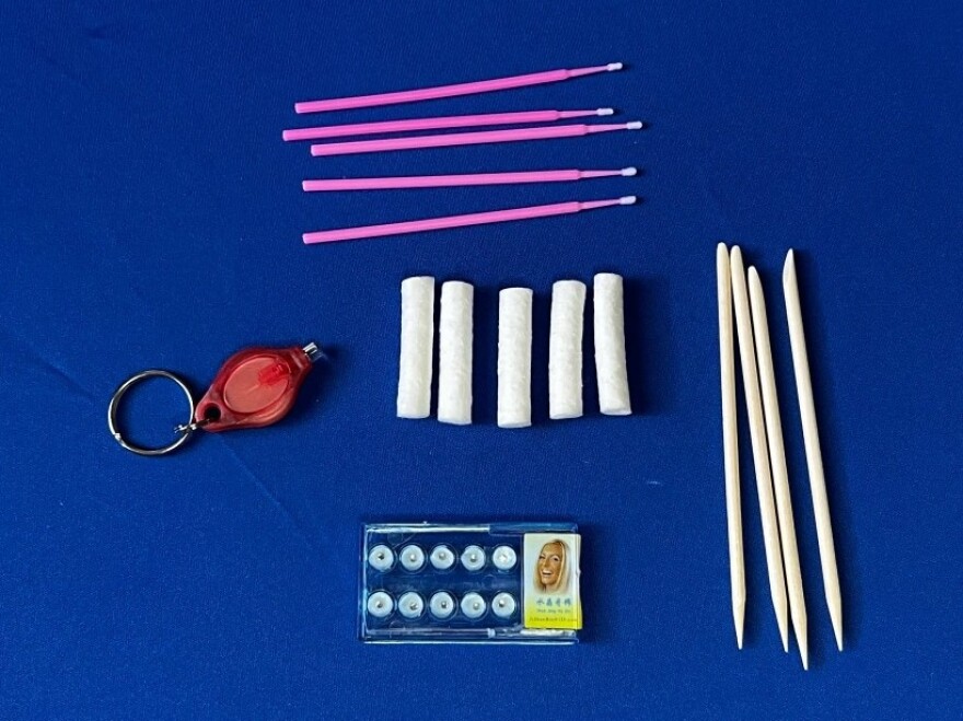 A 25-piece tooth gem kit, sold through Amazon for $12.99, contains 10 rhinestones, one mini-LED keychain to cure the adhesive, four wooden sticks, five disposable applicator brushes, and five cotton rolls. The kit does not come with glue or instructions.