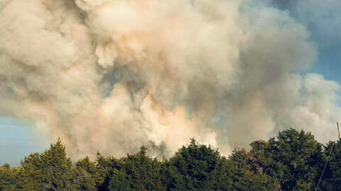 Smoke billows above the tree tops in Caddo County.