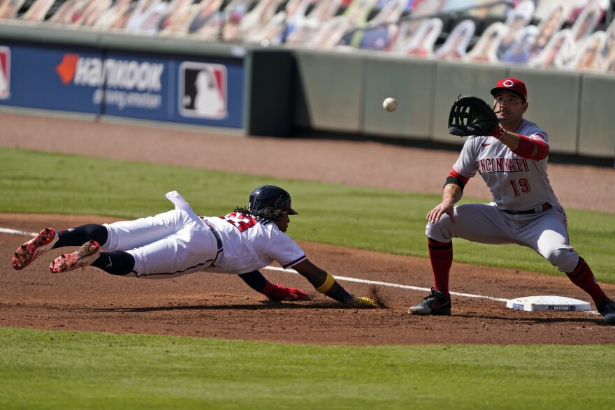 Atlanta Braves' Ronald Acuna Jr. dives back to first base as Cincinnati Reds first baseman Joey Votto reaches for the pick-off throw during the first inning in Game 2 of a National League wild-card baseball series, Thursday, Oct. 1, 2020 in Atlanta.