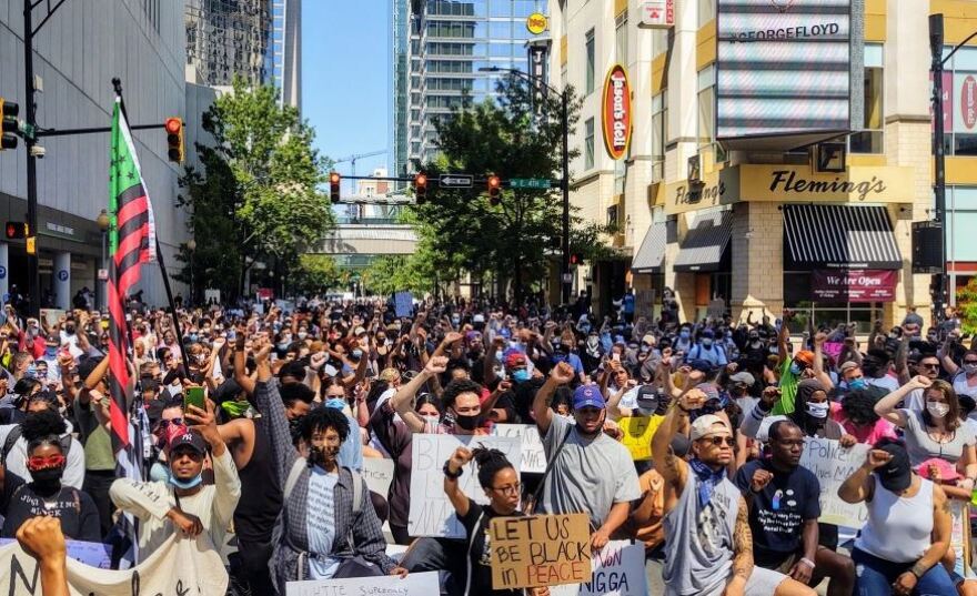 Protesters kneel in uptown Charlotte on May 21, 2020, while observing a moment of silence for George Floyd.