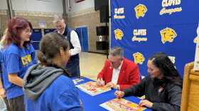 Terry Madigan, Tournament of Roses president, and Esmeralda Rocha Lozano, Clovis High music director, sign Rose Parade posters for band students.