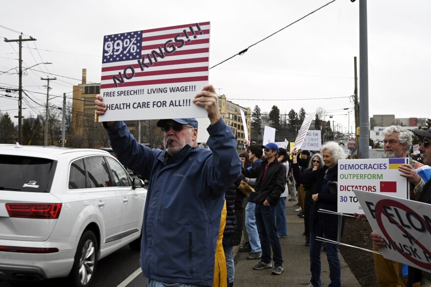 Protesters hold signs criticizing Elon Musk and his electric car company Tesla at a rally in Stamford on March 16, 2025. The protests are part of a nationwide campaign asking people to sell their Tesla vehicles or stock in the company in response to Musk's role in the federal government, including planned mass firings which have been challenged by court orders and scrutinized by critics.