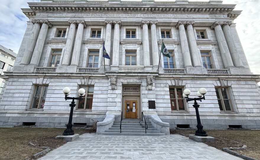 A marble building with stately columns and two flags posted above the main door