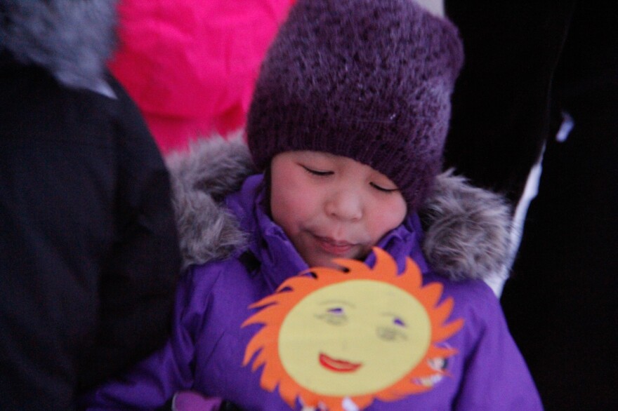 Julianne Kuko, 9, holds a drawing of the sun as she and her classmates perform a song to welcome the first sunrise in 58 days.